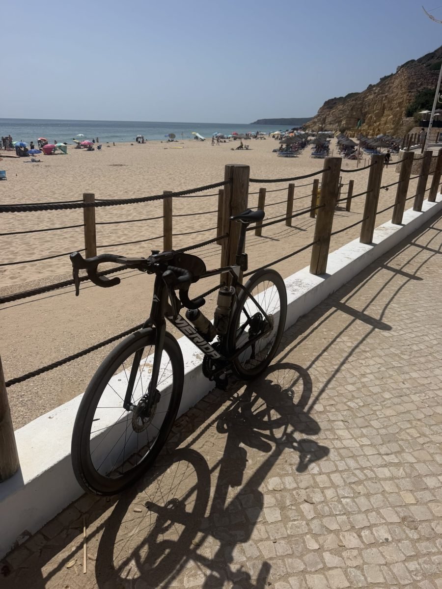 Black road bike leaning on a wooden rail above the beach at Praia de Salema