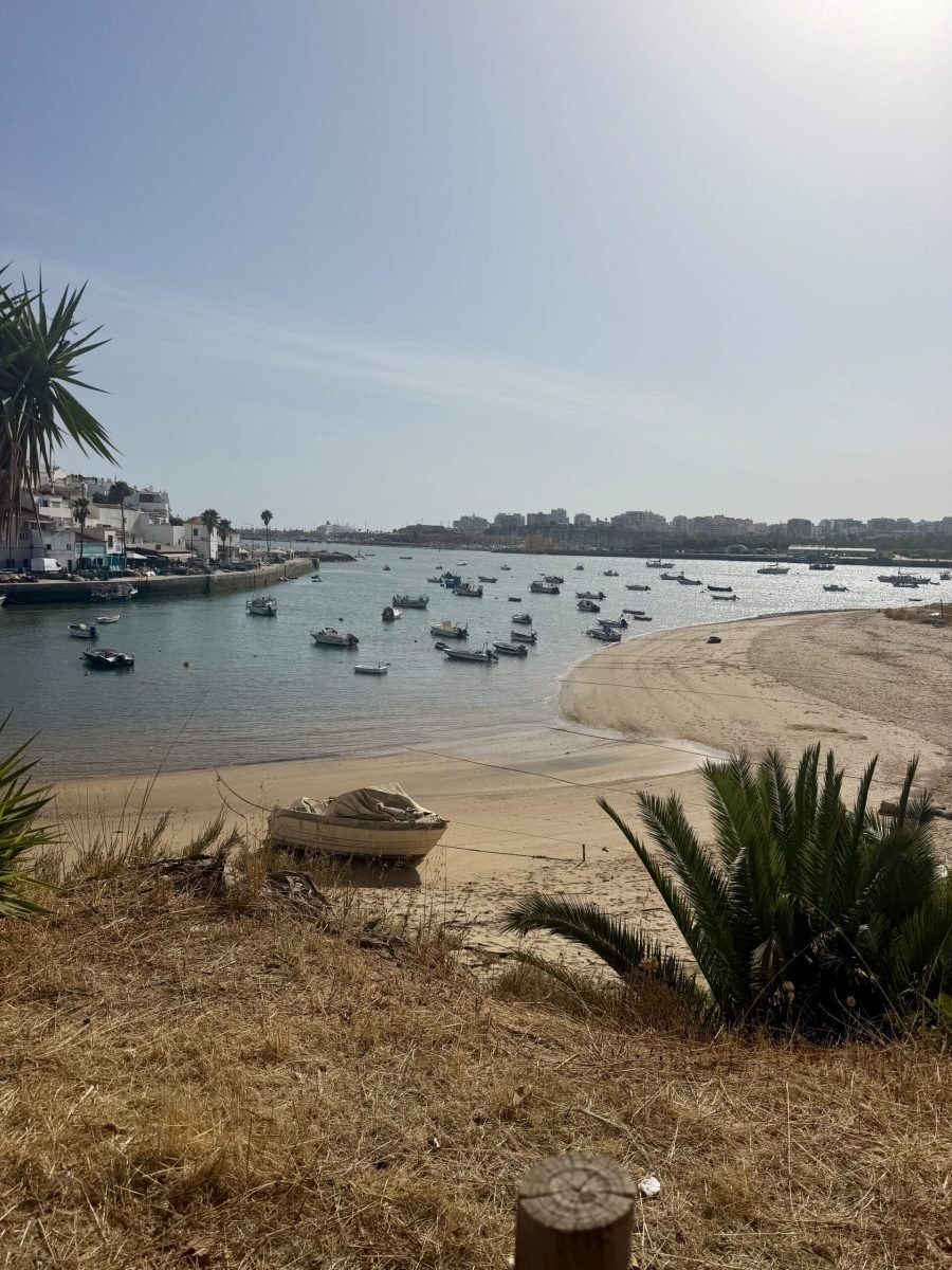 Small fishing boats moored in the Arade estuary at Ferragudo, with a sandy beach in front and Portimão across the water