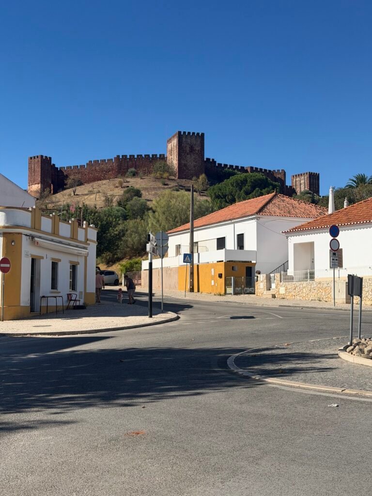 Red sandstone walls and towers of Silves Castle above whitewashed houses on a sunny morning