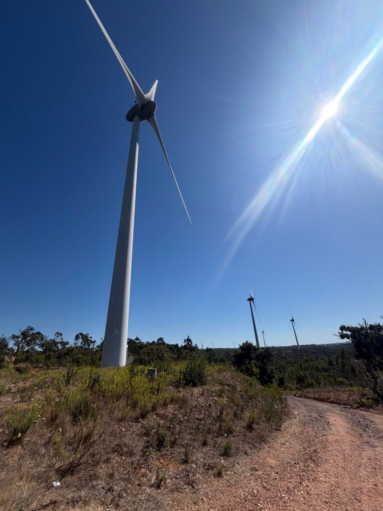 Wind turbine against a bright blue sky beside a gravel track near Alfambras