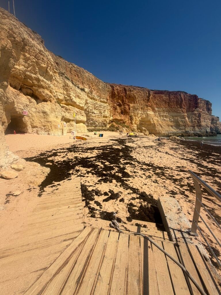 Golden sandstone cliffs and wooden steps leading down to the sand at Benagil