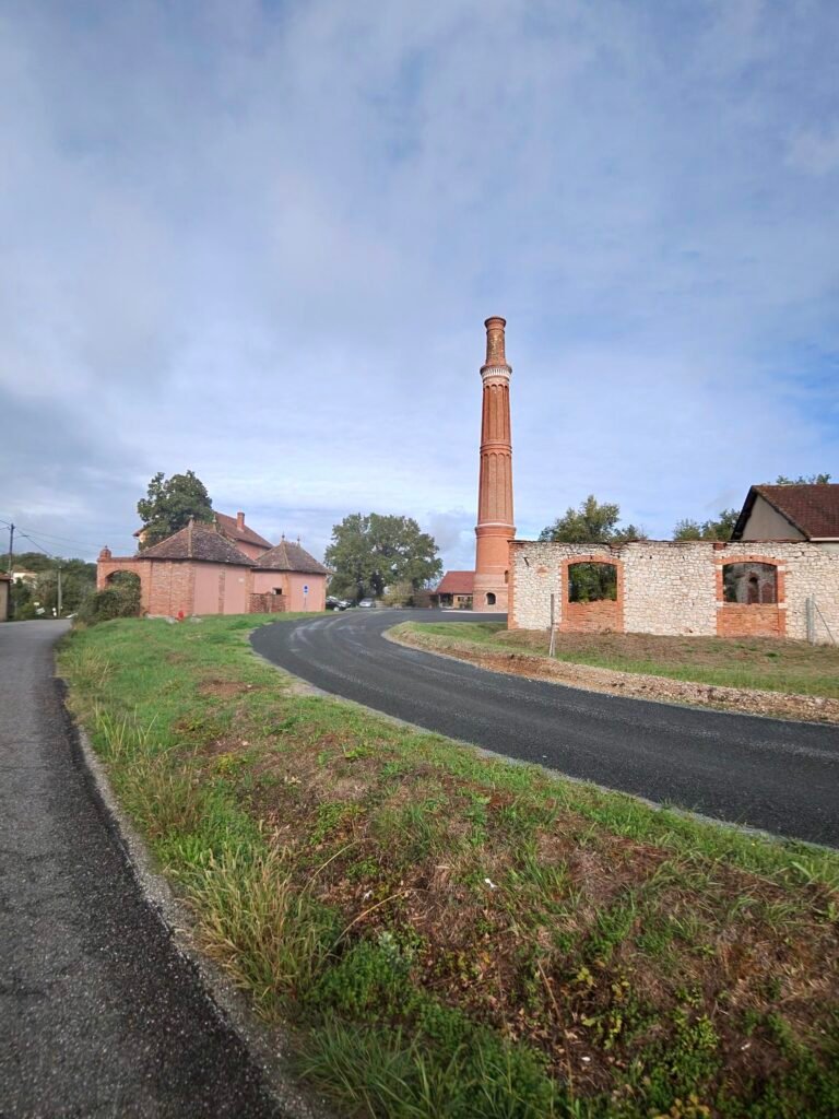 A tall old brick chimney beside a country road under a grey sky
