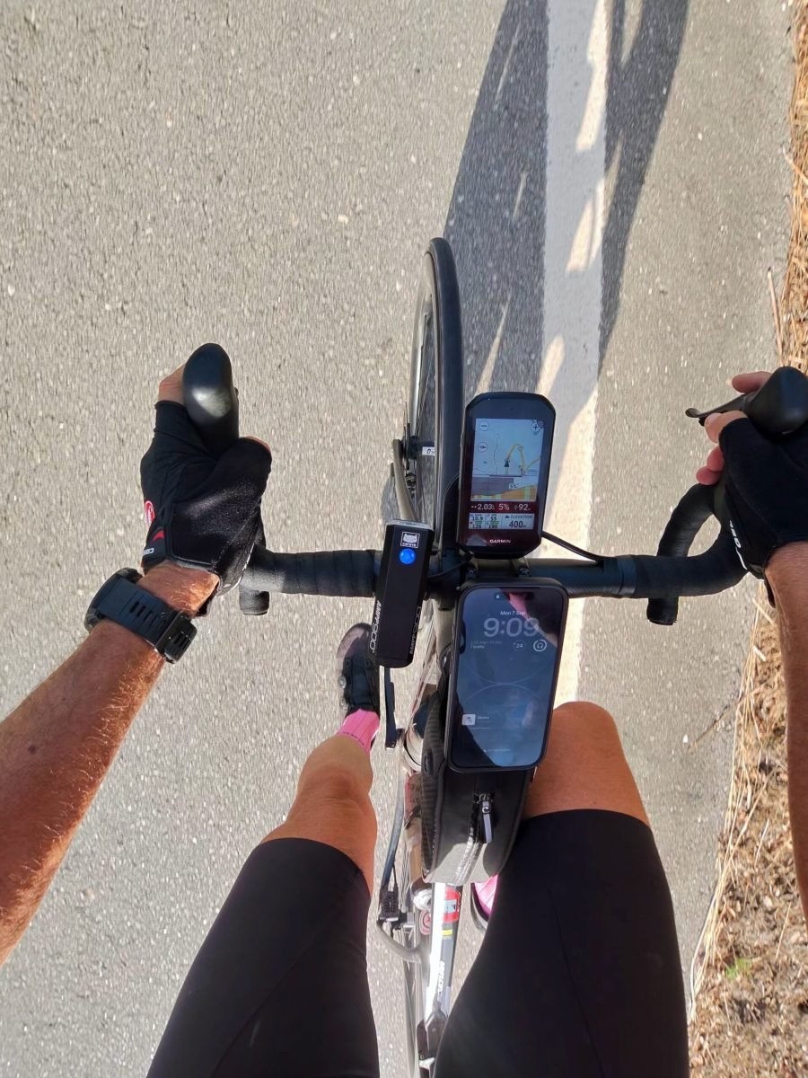 Rider's-eye view of the handlebars, with a Garmin showing 400 m elevation and 2 km to the top of the climb