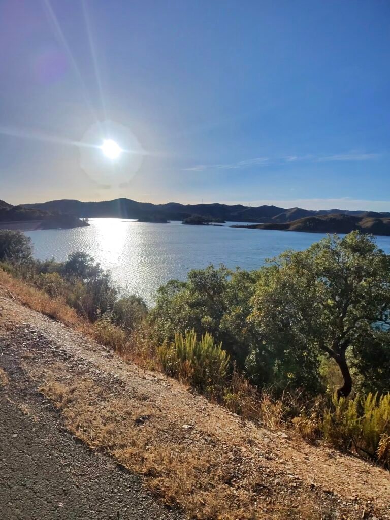 The Arade reservoir glinting under a low sun, seen from the hillside road