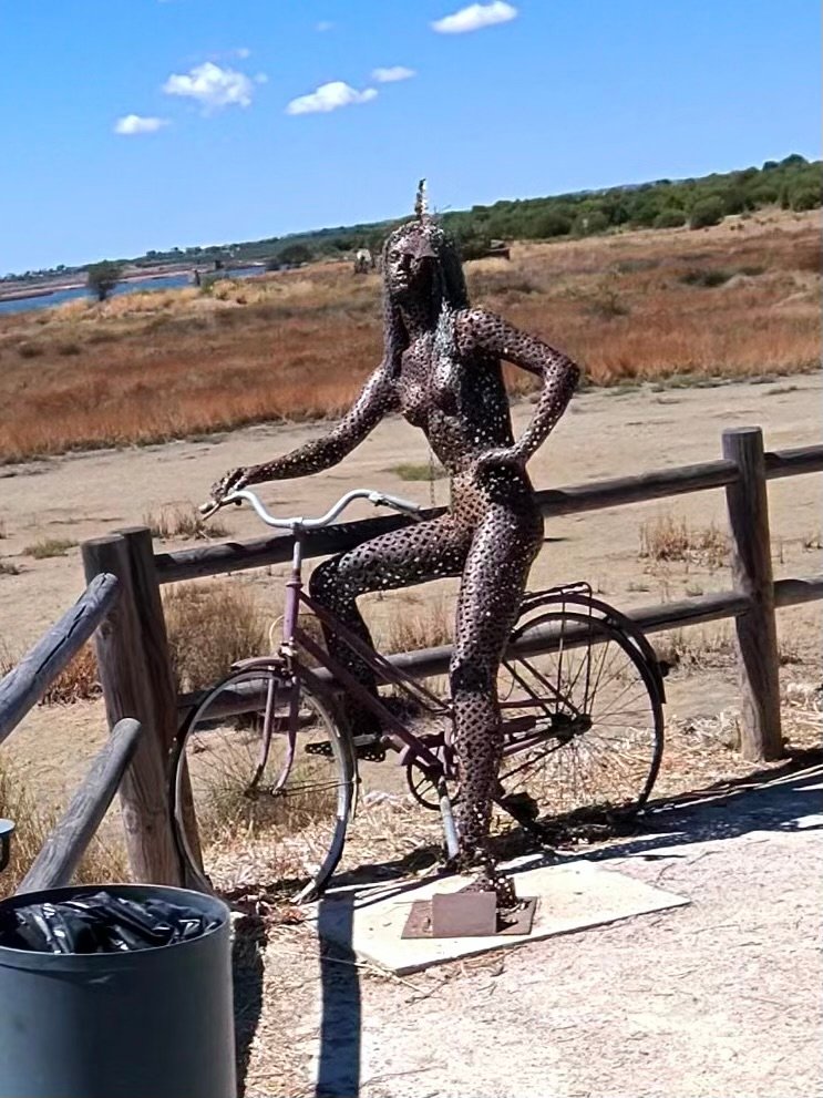 Metal sculpture of a woman riding a bicycle beside the salt marshes at Castro Marim