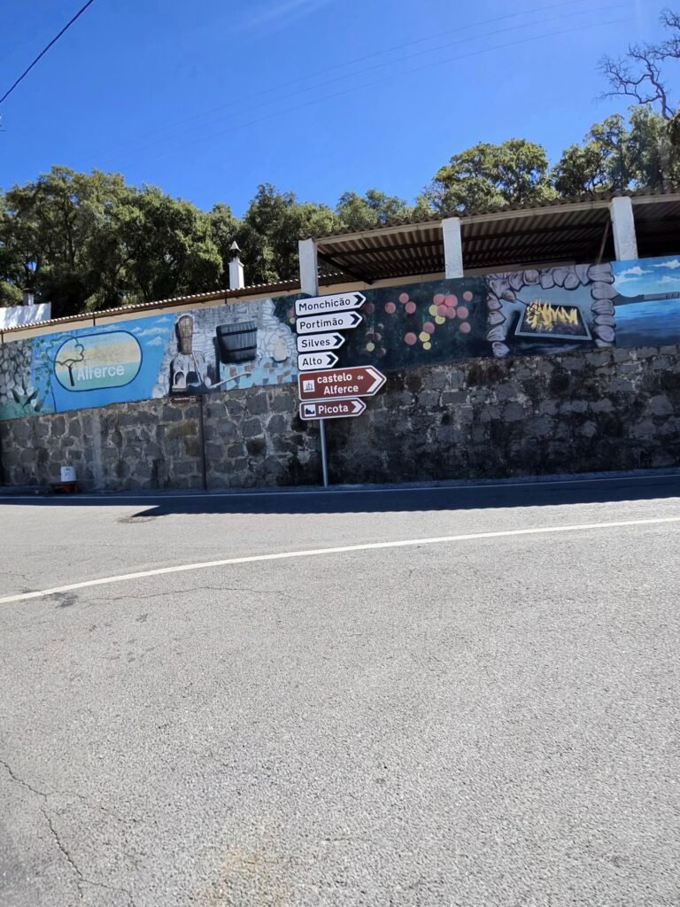 Painted mural wall in Alferce with road signposts to Monchique, Silves, Alte and Picota