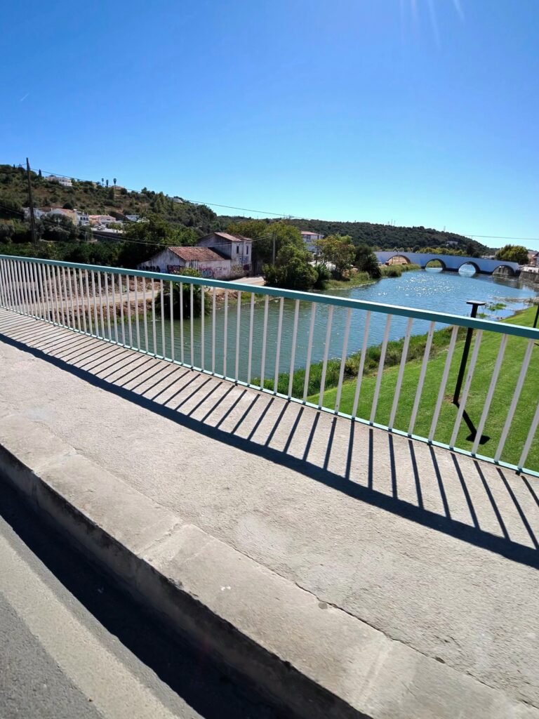 The Arade river and old bridge at Silves seen from behind a riverside railing