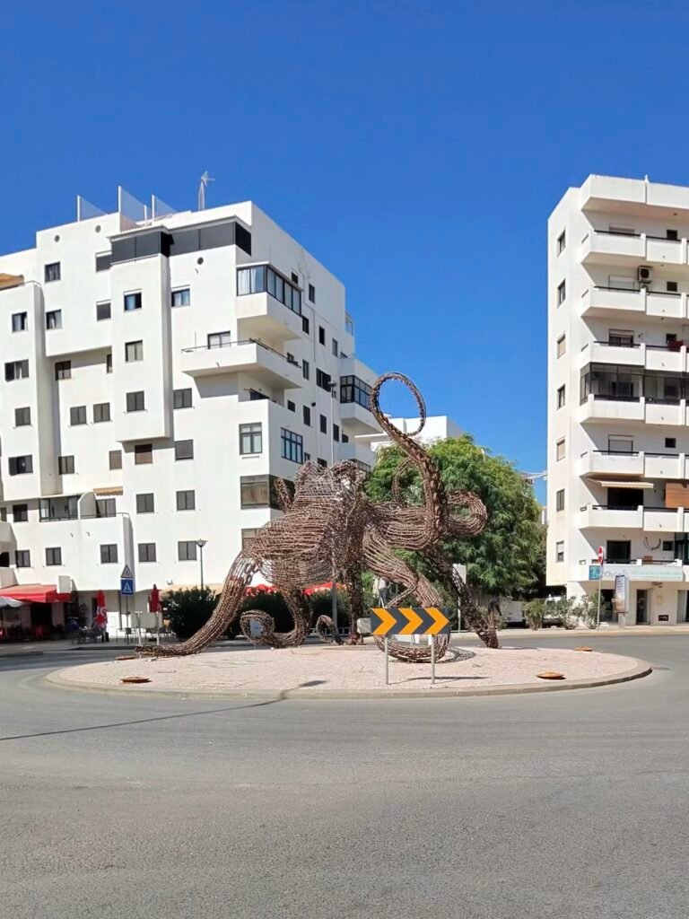 A giant woven sculpture on a roundabout among white apartment blocks in Quarteira